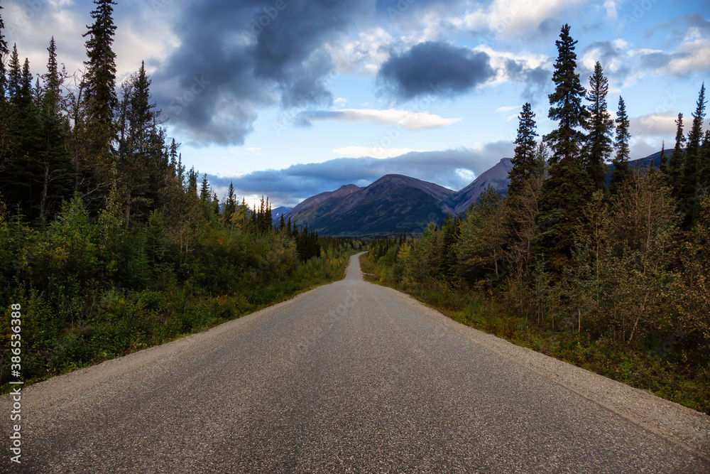 View of Scenic Road surrounded by Trees and Mountains on a Cloudy Fall Morning in Canadian Nature. Taken in Northern British Columbia, Canada.