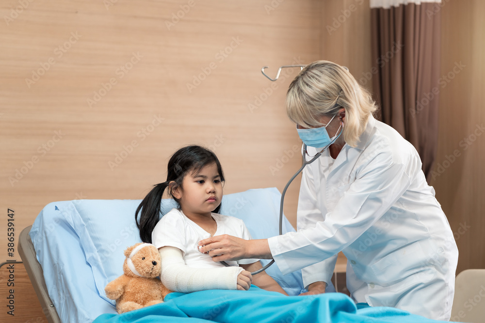 Obraz premium Portarit of smaile doctor pediatrician and little girl patient on bed with teddy bear