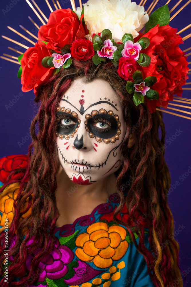 Dia de los muertos - Day of The Dead. Calavera Catrina in Halloween. Close-up portrait young woman with sugar skull make up, flowers and colorful traditional mexican dress. Holy Death - Santa Muerte. Dia de los muertos - Day of The Dead. Calavera Catrina in Halloween. Close-up portrait young woman with sugar skull make up, flowers and colorful traditional mexican dress. Holy Death - Santa Muerte.