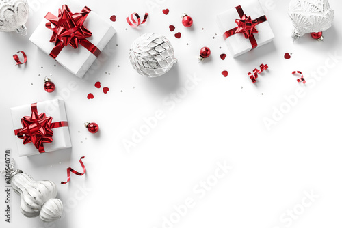 Merry Christmas card made of gift boxes, red and silver decoration, sparkles and confetti on white background. Xmas and New Year holiday, bokeh, light. Flat lay, top view, frame