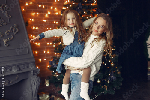 Beautiful mother in a white sweater. Family with cristmas gifts. Little girl near christmas tree