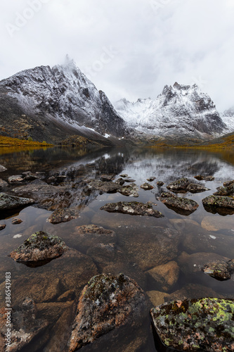 Fototapeta Naklejka Na Ścianę i Meble -  Beautiful View of Scenic Alpine Lake, Rocks and Snowy Mountain Peaks on a Cloudy Fall Day in Canadian Nature. Taken at Grizzly Lake in Tombstone Territorial Park, Yukon, Canada.