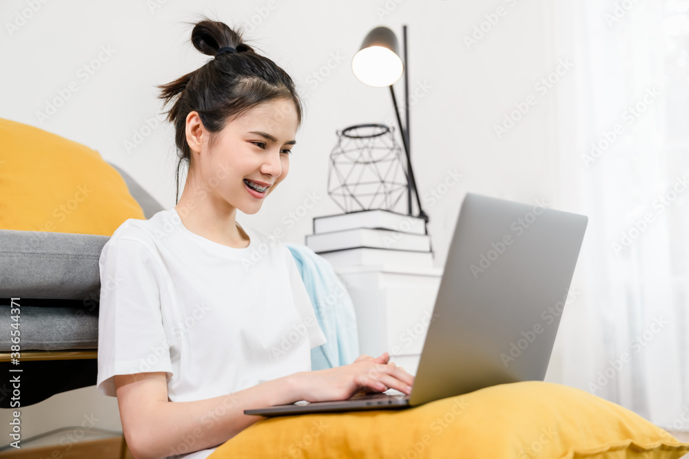 Happy young Asian woman working for laptop with graph documents from home on the sofa, meeting and training online concept. Happy young Asian woman working for laptop with graph documents from home on the sofa, meeting and training online concept.