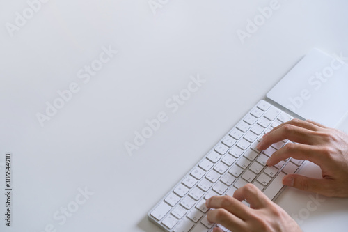 Man typing on the  modern wireless keyboard and trackpad on the desk. Office and working space has benn arranged in minimal modern style. photo