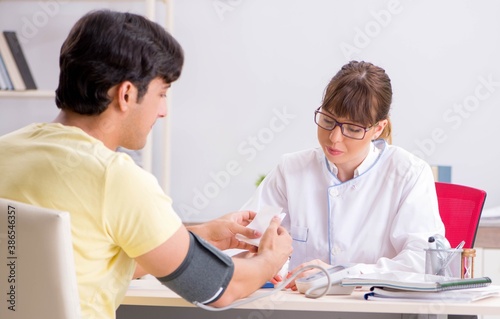 Young doctor checking patients blood pressure