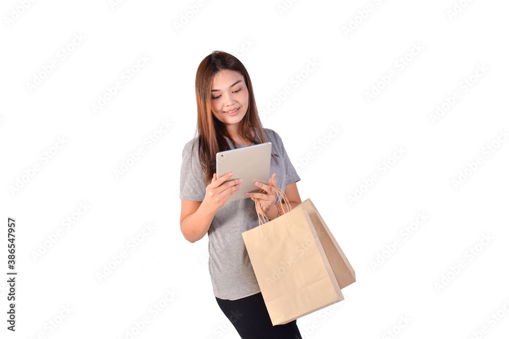 Asian woman holding shopping bags doing online shopping on her tablet on white background. Black Friday sale concept. Asian woman holding shopping bags doing online shopping on her tablet on white background. Black Friday sale concept.