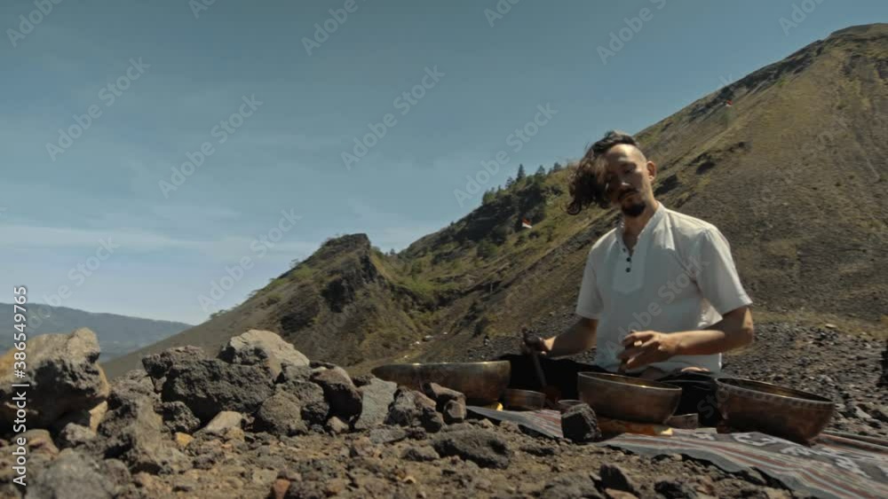 Asian guy playing Tibedt singing copper cups on a viewing mountain Asian guy playing Tibedt singing copper cups on a viewing mountain