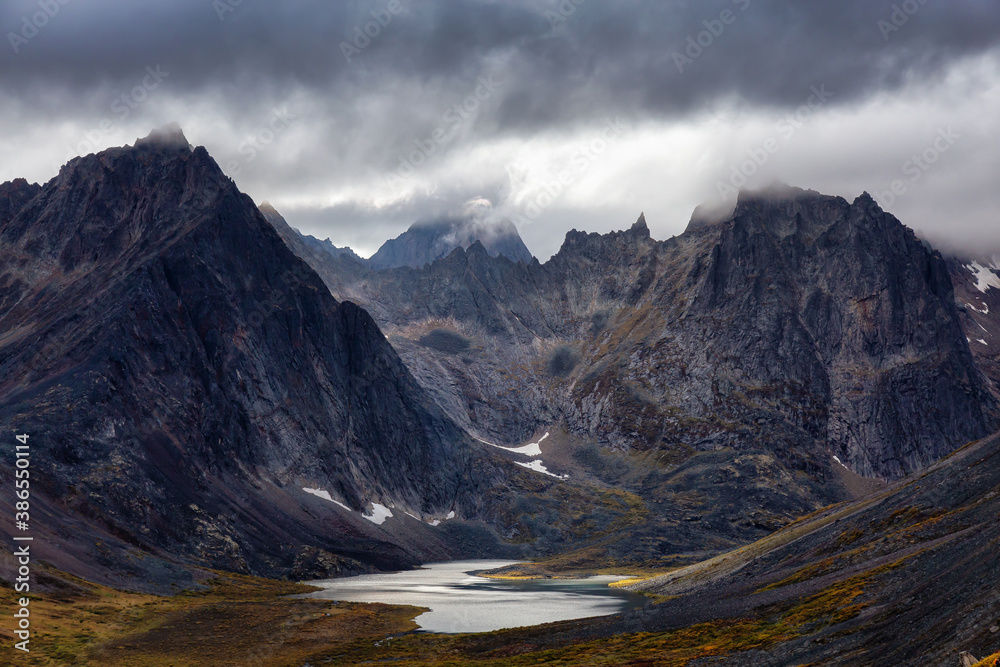 Beautiful View of Dramatic Mountains and Scenic Alpine Lake during Fall in Canadian Nature. Aerial Shot. Taken in Tombstone Territorial Park, Yukon, Canada.