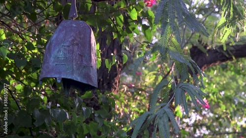 Close-up of a metal garden bell hanging in a desert mesquite tree. photo
