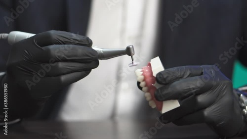 Dental specialist making dentures with a small machine. Polishing fake teeth prostheses.  photo