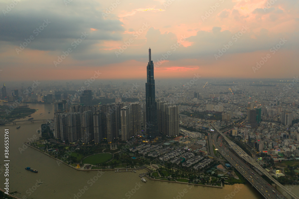 Aerial urban colorful sunrise panorama with high rise building disappearing into the clouds, city center skyline and suburban sprawl