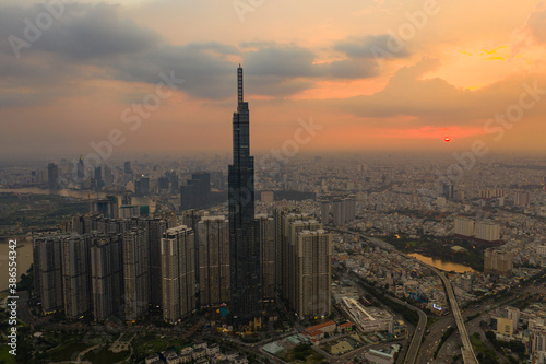 Aerial urban colorful sunrise panorama with high rise building disappearing into the clouds, city center skyline and suburban sprawl © Nhut