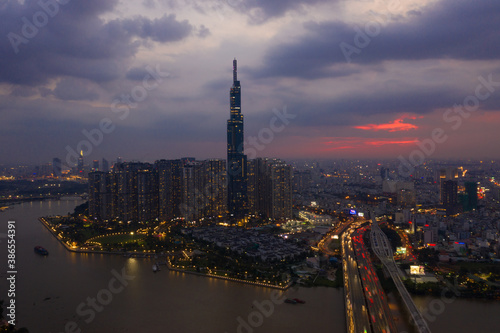 Aerial urban colorful sunrise panorama with high rise building disappearing into the clouds, city center skyline and suburban sprawl