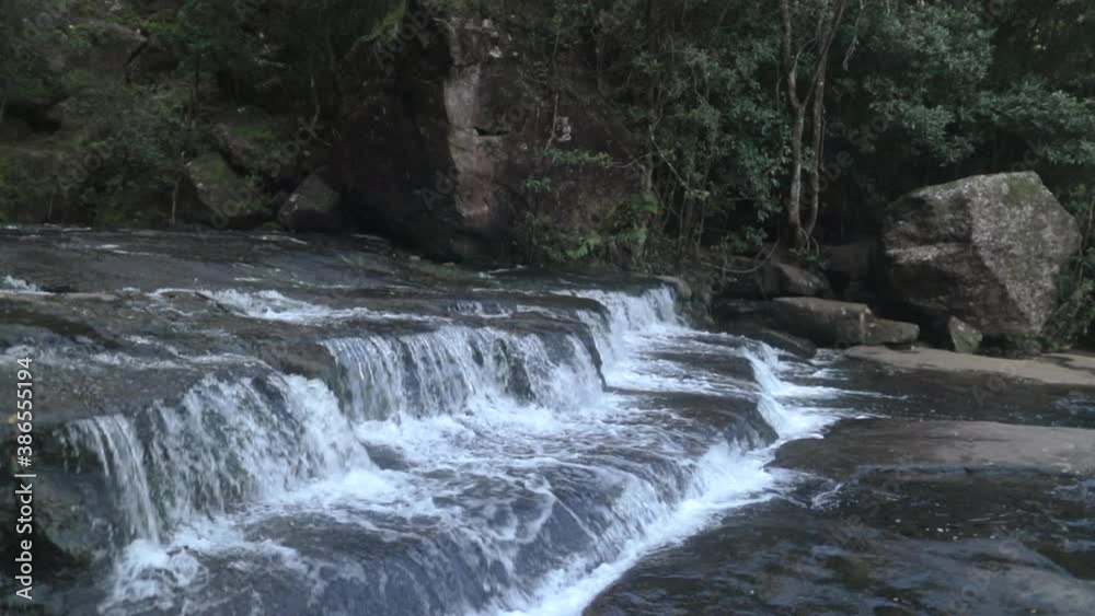tracking shot of small waterfall overhang into plunge pool tracking shot of small waterfall overhang into plunge pool