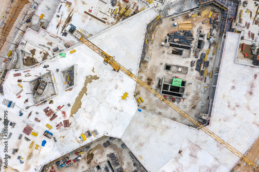 new concrete building under construction. construction site with crane, construction machinery and materials. top view from drone