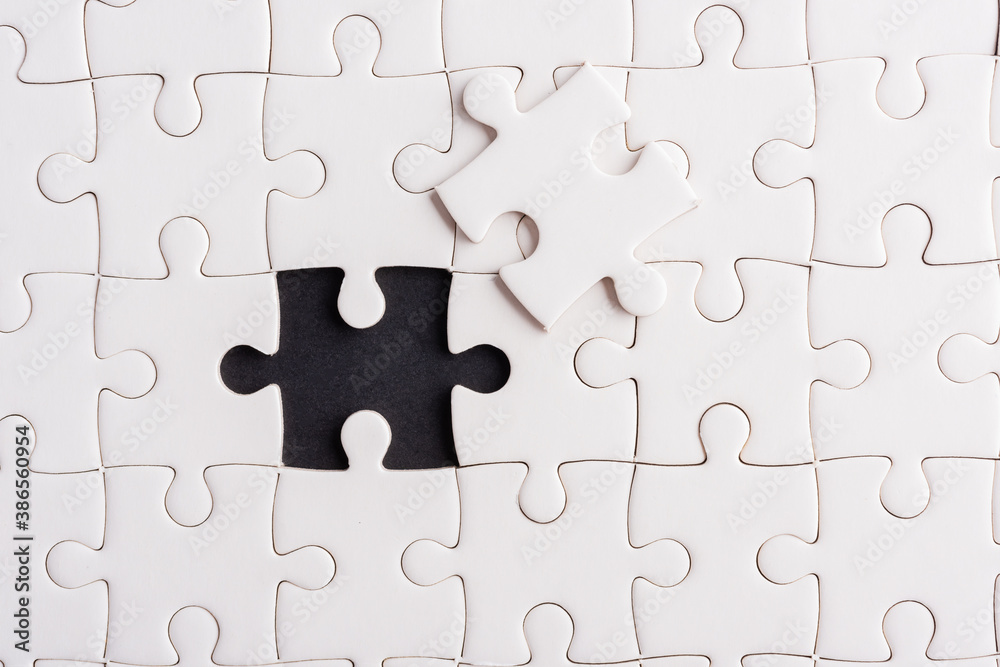 Top view flat lay of paper plain white jigsaw puzzle game texture incomplete or missing piece, studio shot on a black background, quiz calculation concept Top view flat lay of paper plain white jigsaw puzzle game texture incomplete or missing piece, studio shot on a black background, quiz calculation concept