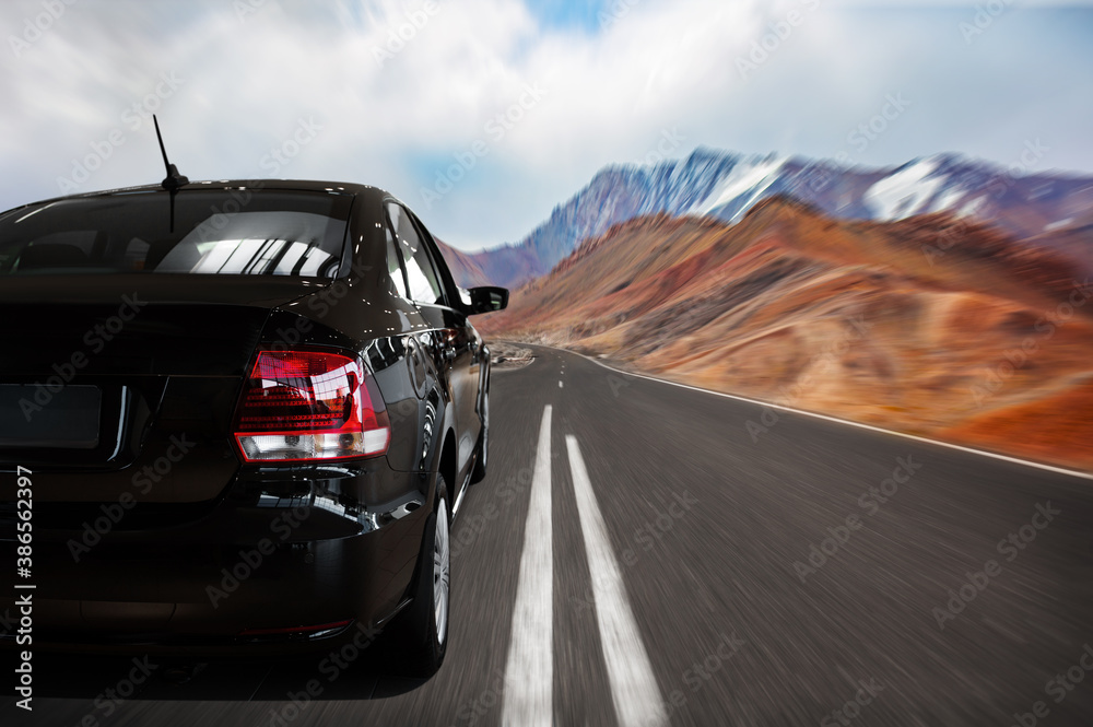 Naklejka premium Close-up of a black car on the highway. travel by car. high-speed road along the mountains