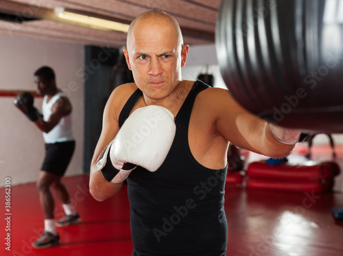 Confident boxer man training on punching bag. High quality pot © JackF