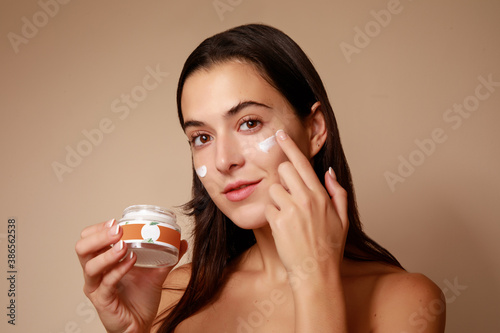 Joven Mujer mexicana probando crema humectante facial producto de belleza feliz sonriente photo