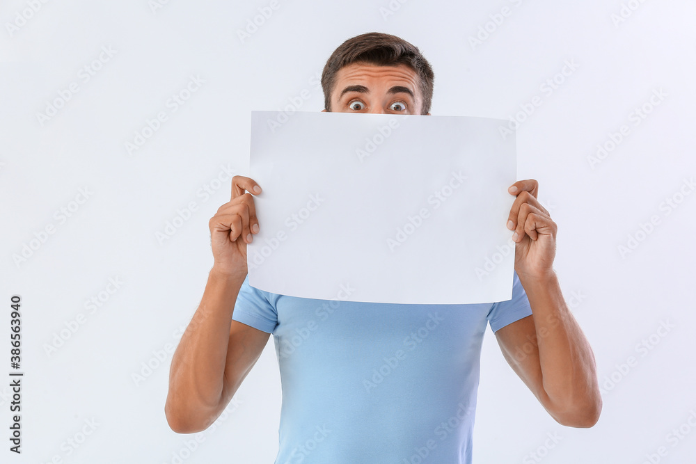 Surprised young man with blank paper sheet on white background Surprised young man with blank paper sheet on white background