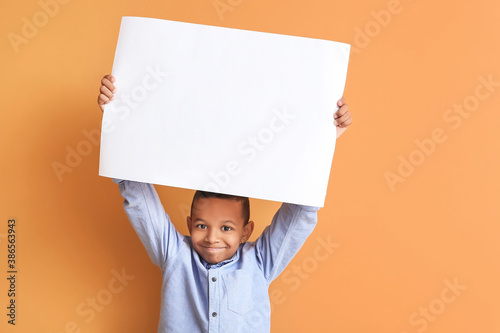 Little African-American boy with blank poster on color background photo