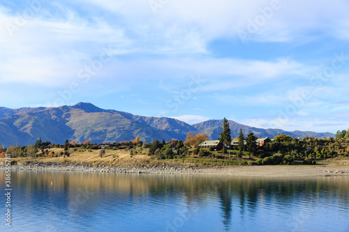 Peaceful autumn landscape with solitary holiday boat on the calm waters with beautiful mountain background at Lake Hawea, New Zealand.