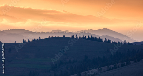 Orange and yellow sunset with mountains silhouettes. Gradient vivid nature background. Ukraine © Taiga
