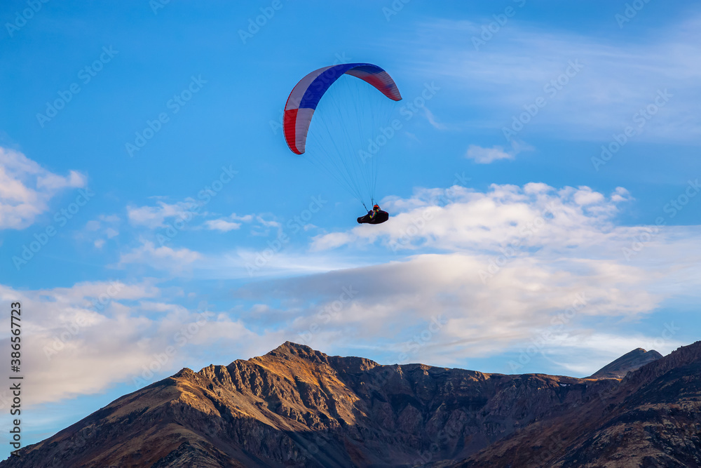 Paraglider flying over Scenic Mountain Range, surrounded by Clouds in Canadian Nature. Taken in Tombstone Territorial Park, Yukon, Canada. Paraglider flying over Scenic Mountain Range, surrounded by Clouds in Canadian Nature. Taken in Tombstone Territorial Park, Yukon, Canada.