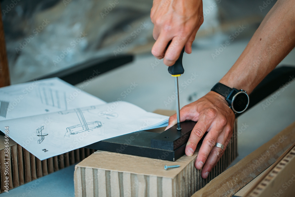 Shallow focus images of man assembling furniture at home using a screwdriver. Shallow focus images of man assembling furniture at home using a screwdriver.