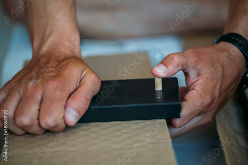 Shallow focus images of man assembling furniture at home using a screwdriver.