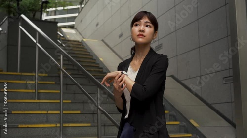 Japanese business woman looking at her watch impatiently, waiting for someone important for a meeting. Asian female worker in a company.