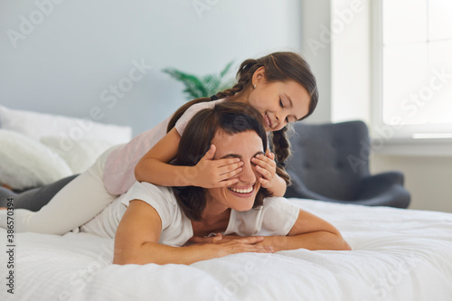 Konstfotografi Happy mother and daughter spending time at home and relaxing on soft bed in quie
