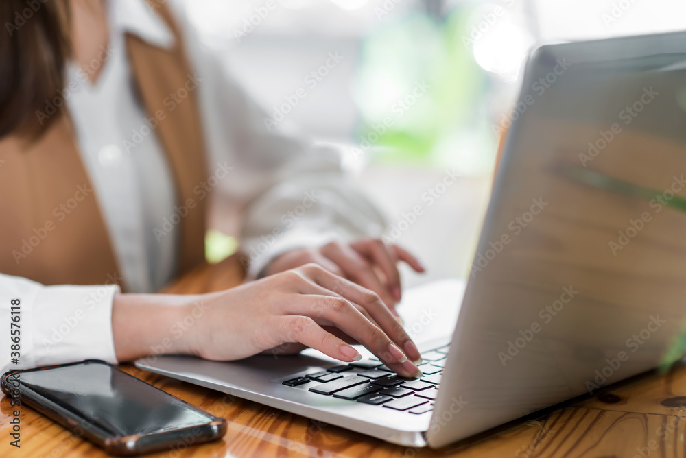 Close up. Woman sitting at desk and working at laptop computer. Close up. Woman sitting at desk and working at laptop computer.