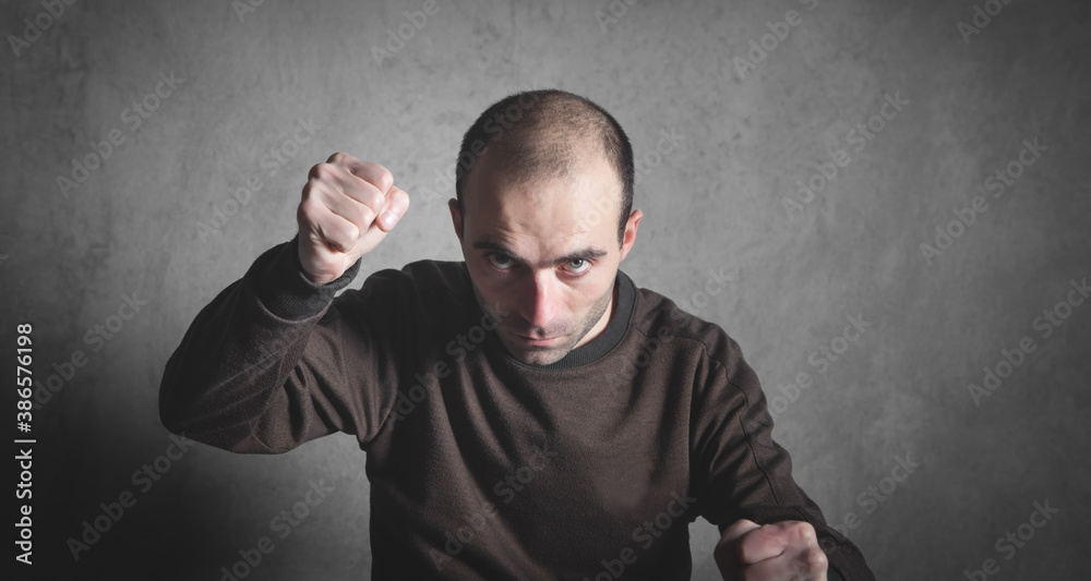 Caucasian angry and aggressive man threatening with fists.