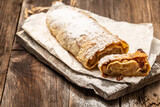 Homemade pear strudel, decorated with cinnamon, raisins powdered sugar on a rustic background. Food recipe background