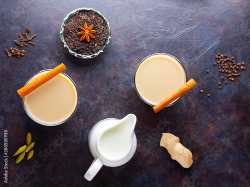 Masala chai tea. Traditional indian drink - masala tea with various spices. Two glasses with masala tea on a dark background