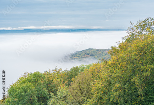 View from a mountain into the misty valley, in the background you can see some wind turbines in the distance