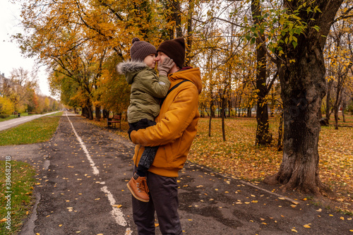 Father have a fun with his little son in a park. Autumn colors, green, orange. Son kiss dad on the alley. © Татьяна Максимова