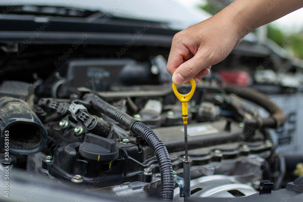 Auto repair center, an auto mechanic's hand, is checking the engine oil level so the car is ready to go long distances. Auto repair center, an auto mechanic's hand, is checking the engine oil level so the car is ready to go long distances.