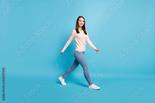 Full length body size profile side view of her she nice attractive pretty lovely charming cheerful cheery brown-haired girl going isolated over bright vivid shine vibrant blue color background