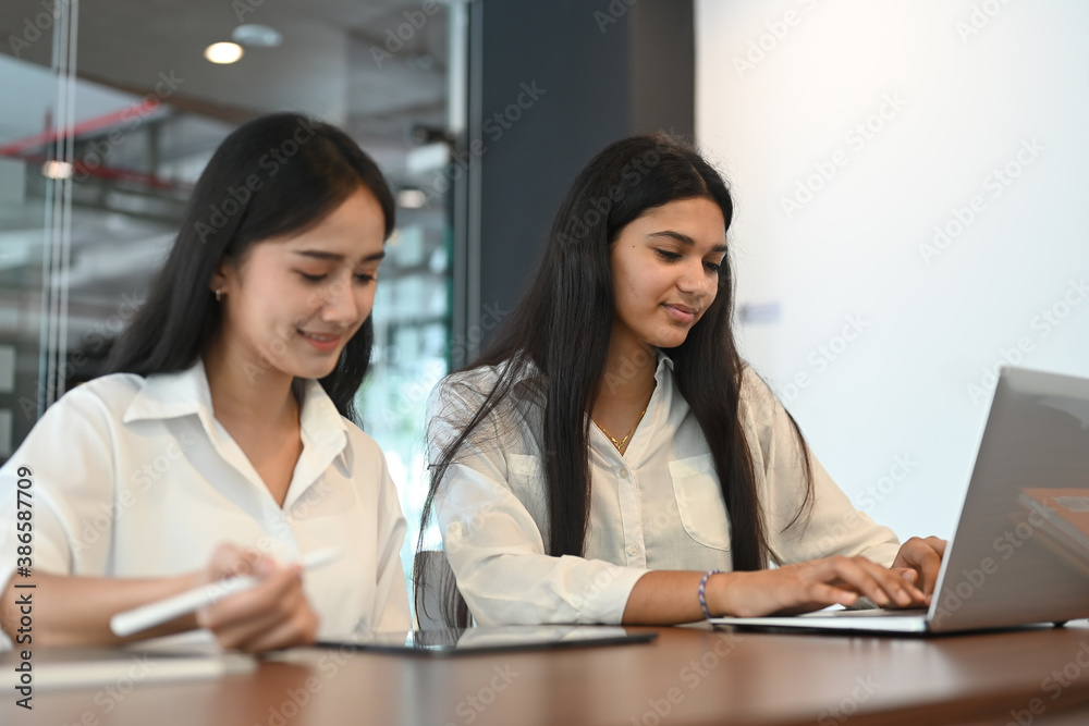 Successful young female coworkers working together on computer inside office. Successful young female coworkers working together on computer inside office.