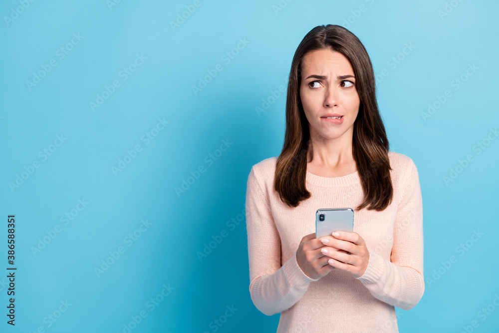 Portrait of her she nice attractive pretty worried brown-haired girl using device looking aside copy space biting lip isolated over bright vivid shine vibrant blue color background Portrait of her she nice attractive pretty worried brown-haired girl using device looking aside copy space biting lip isolated over bright vivid shine vibrant blue color background