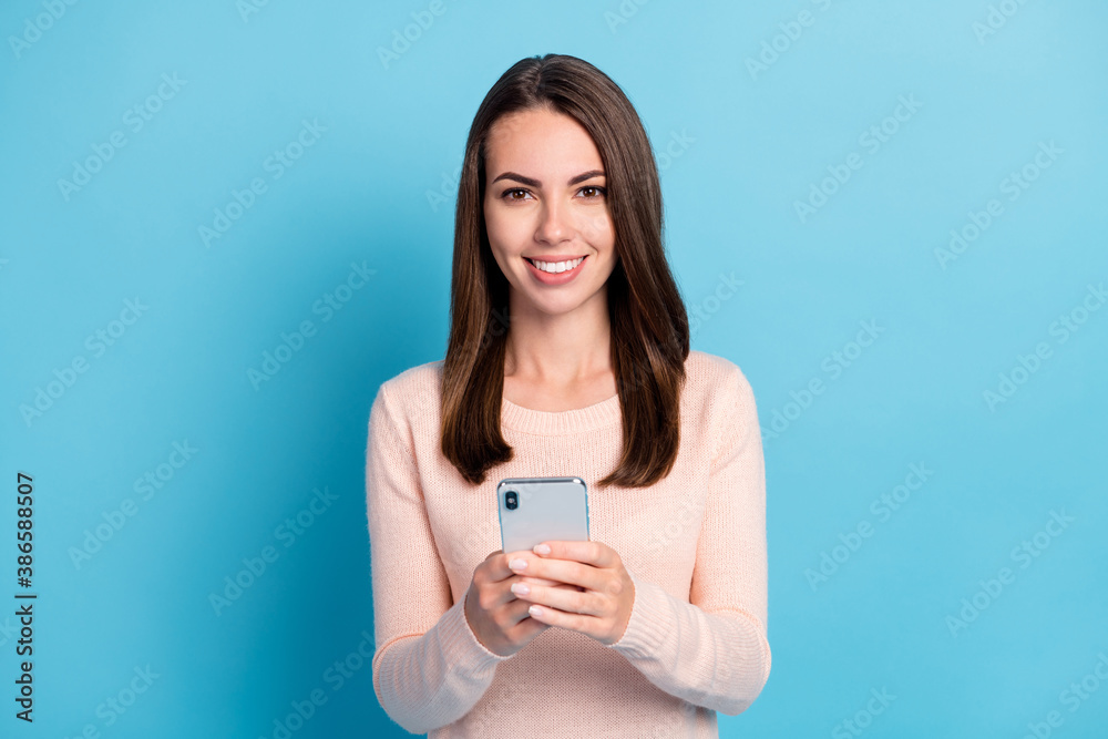 Photo of positive cheerful girl hold cellphone wear pastel pullover isolated over blue color background Photo of positive cheerful girl hold cellphone wear pastel pullover isolated over blue color background