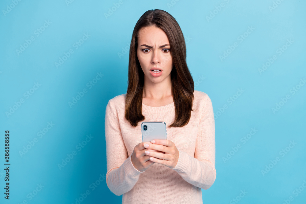Photo of shocked girl read social media information on cellphone wear pastel clothes isolated over blue color background Photo of shocked girl read social media information on cellphone wear pastel clothes isolated over blue color background