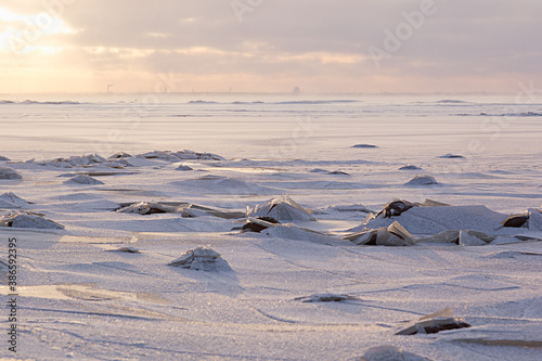 Soft light golden sunset in winter over frozen coast with broken ice, horizont, sunbeams and shiny snow, landscape in pastel pink and blue color. © finepoints
