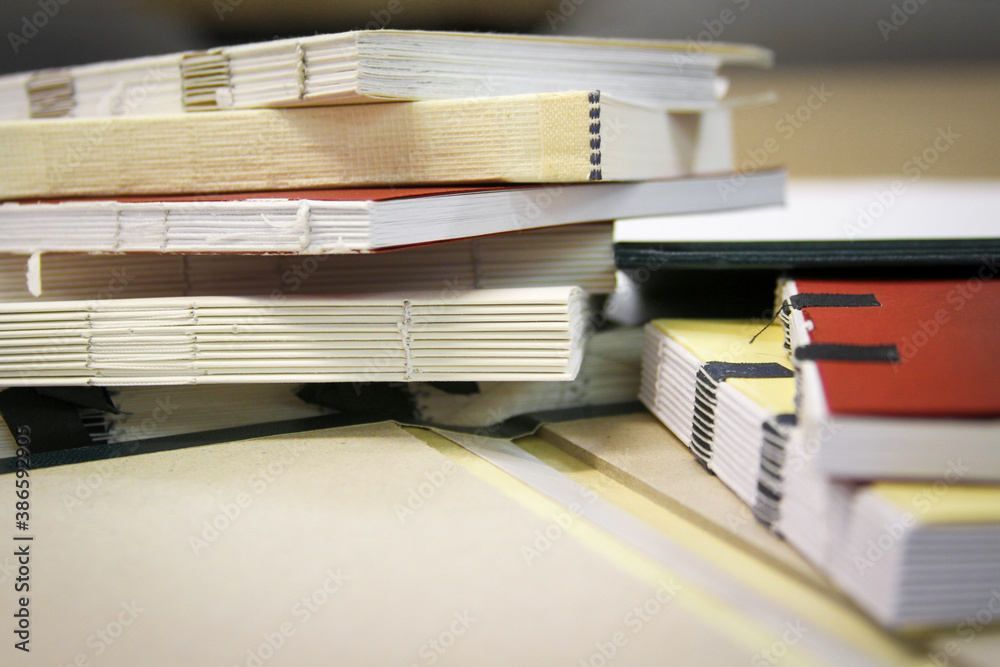 Close up photography of a pile of semifinished bound books in selective focus. Class work of printing students. - obrazy, fototapety, plakaty 