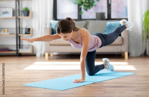 sport, fitness and exercising concept - happy young woman doing elbow knee crunches at home