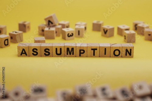 ASSUMPTION Word Written In Wooden Cube With Yellow Background
