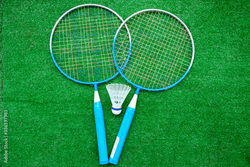 Two badminton mini rackets with white shuttlecock on the green background, active games