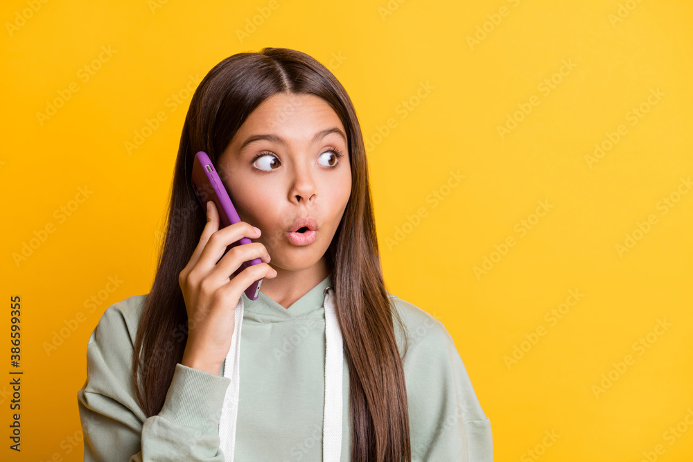 Photo of surprised child girl dressed casual green outfit communicating device looking empty space isolated yellow color background Photo of surprised child girl dressed casual green outfit communicating device looking empty space isolated yellow color background